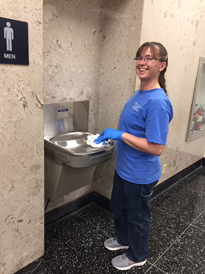 A facilities employee works on a drinking fountain